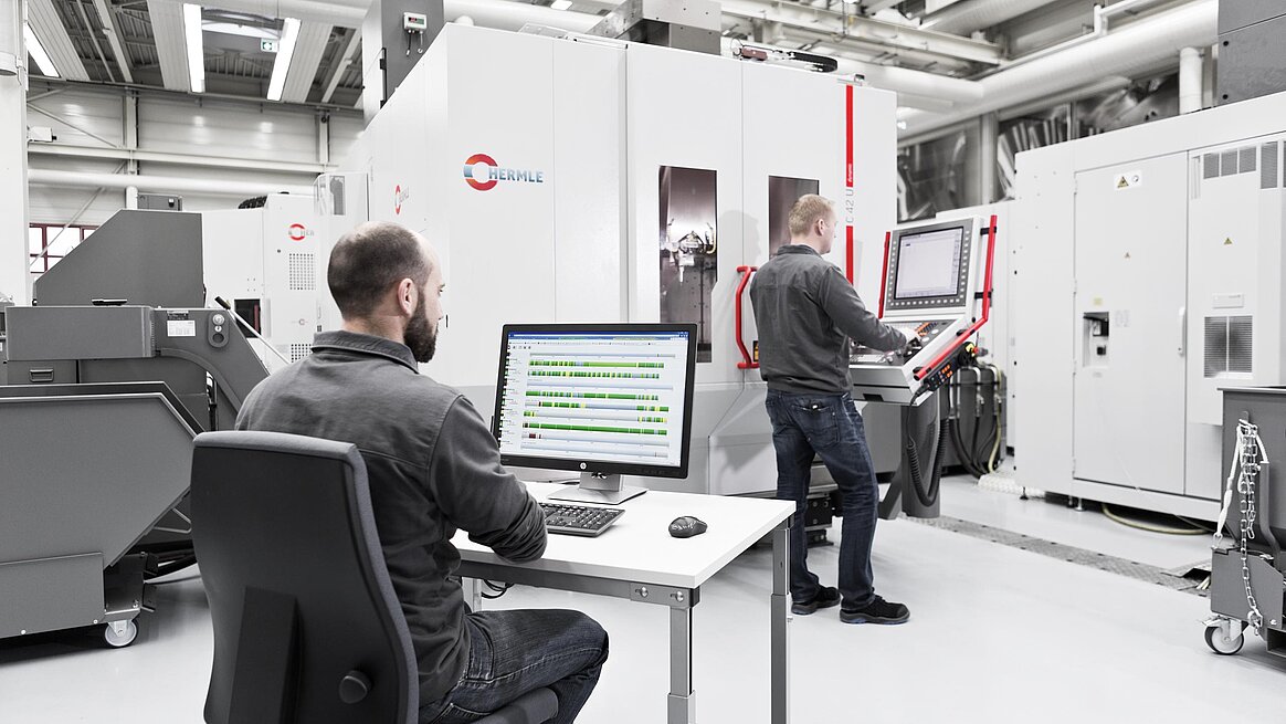 CNC Fertigung durch zwei Mitarbeiter vor Hermle Bearbeitungszentrum