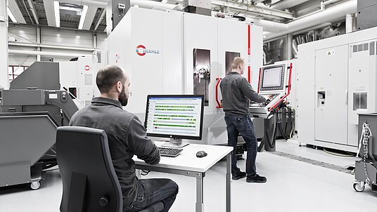 CNC Fertigung durch zwei Mitarbeiter vor Hermle Bearbeitungszentrum