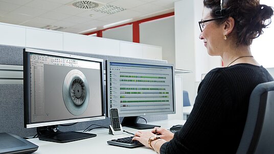 Eine MItarbeiterin sitzt vor dem Computer und bedient die CNC-Software