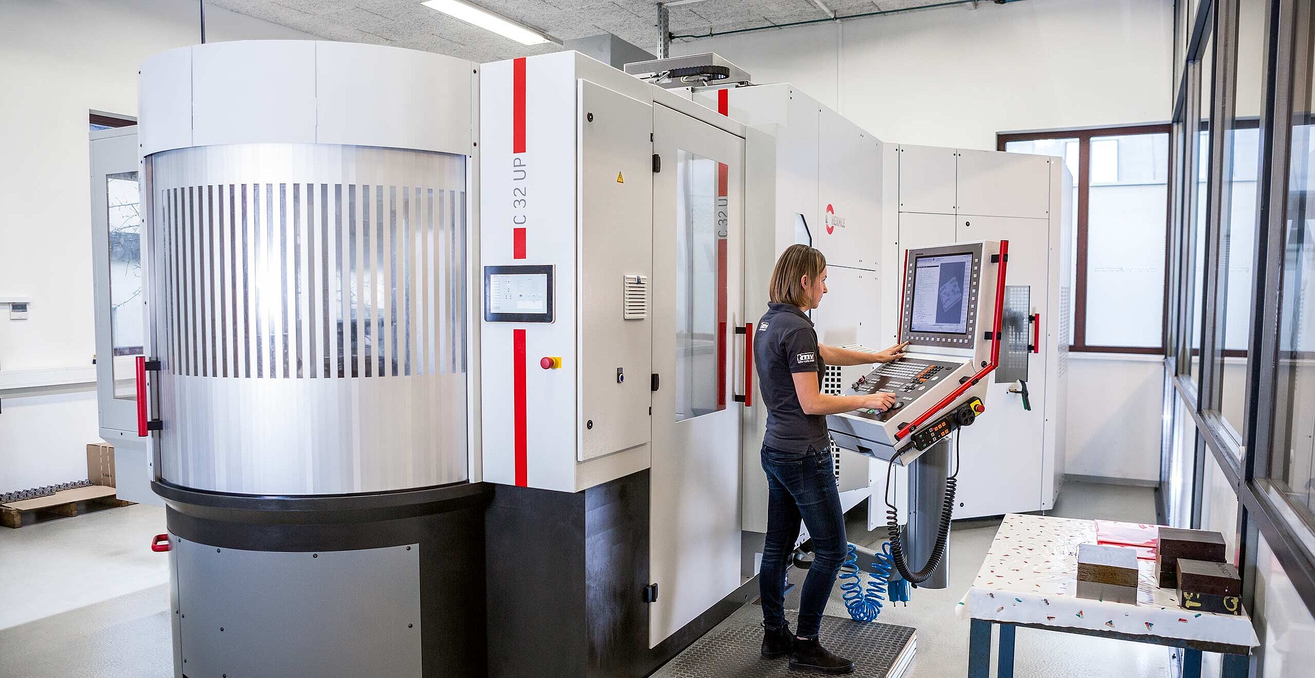 An overall view of the Hermle high-performance, 5-axis Hermle C 32 U CNC machining centre with a PW 250 pallet changer with storage; the PW 250 setup station is located at the front 