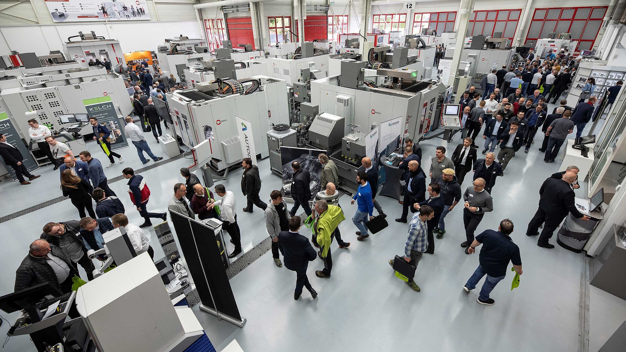 Besucher der Hermle Hausmesse schauen sich die ausgestellten Maschinen an