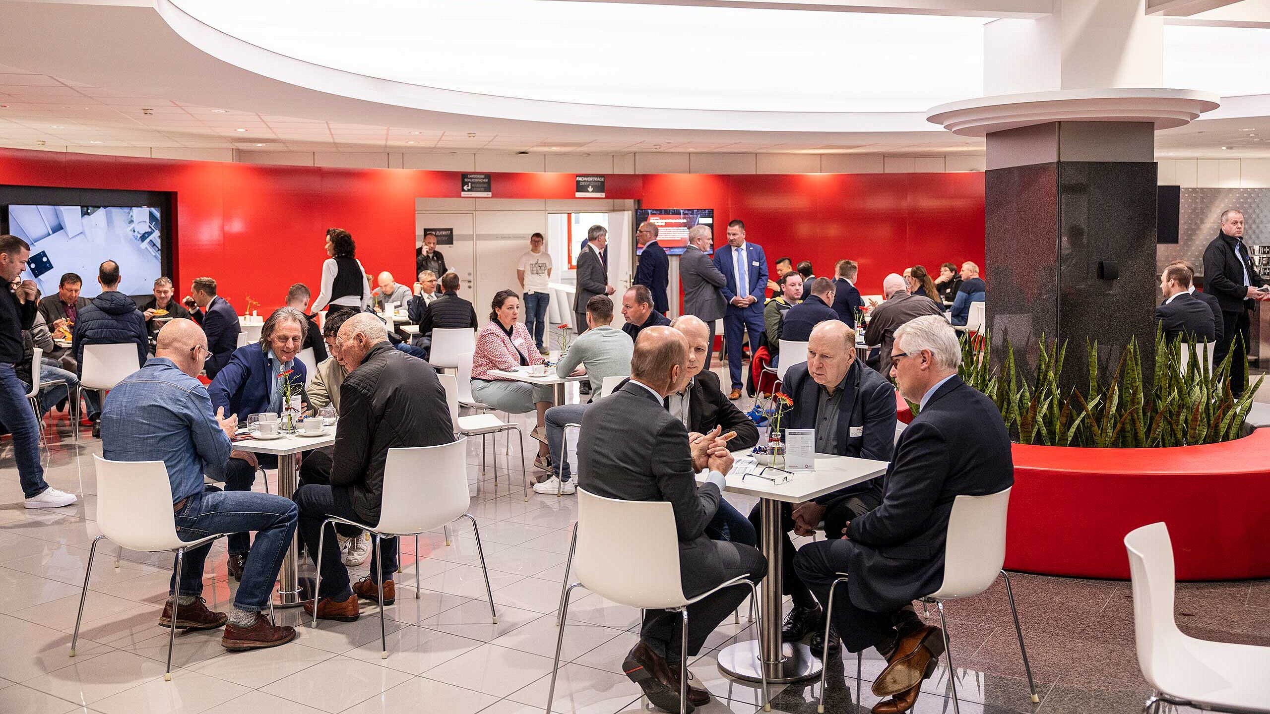 Besucher der Hermle Hausausstellung sitzen an Tischen und unterhalten sich