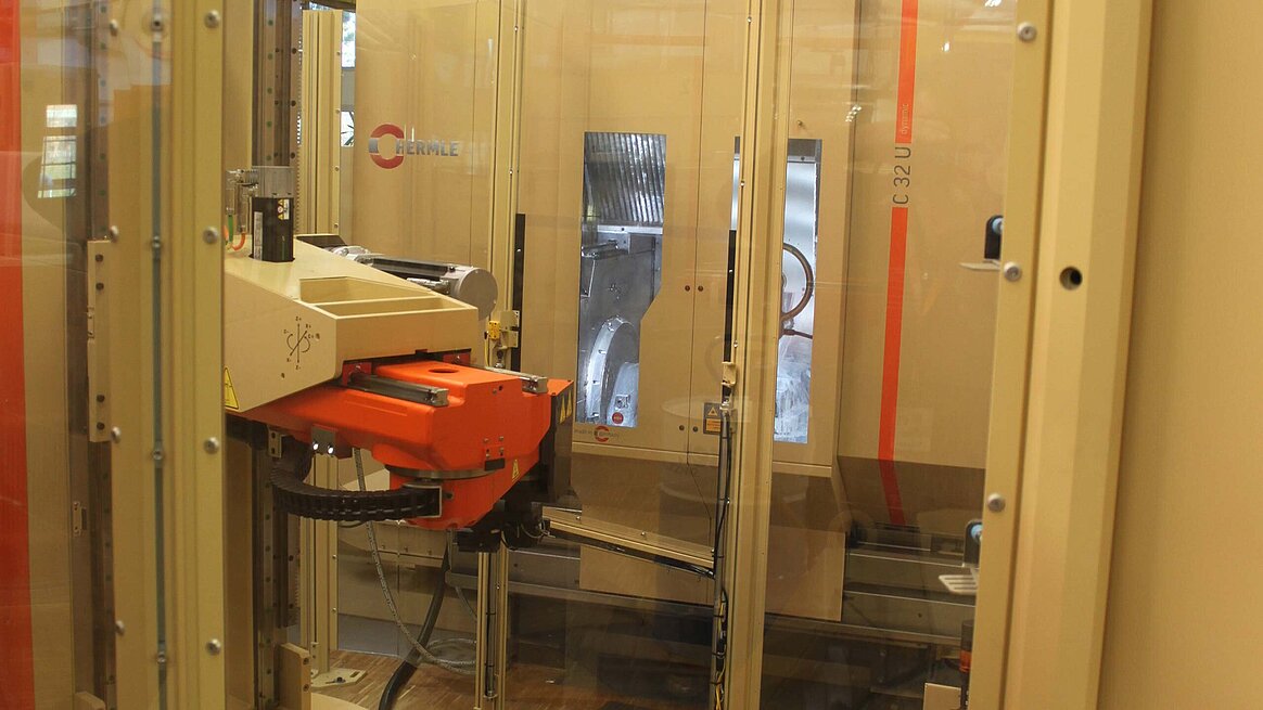 A perspective from the workpiece magazine, located on the left, through the rotating portal handling device which supplies the two machining centres, to the automatically opening and closing cabin door to the working area of the C 32 U machining centre