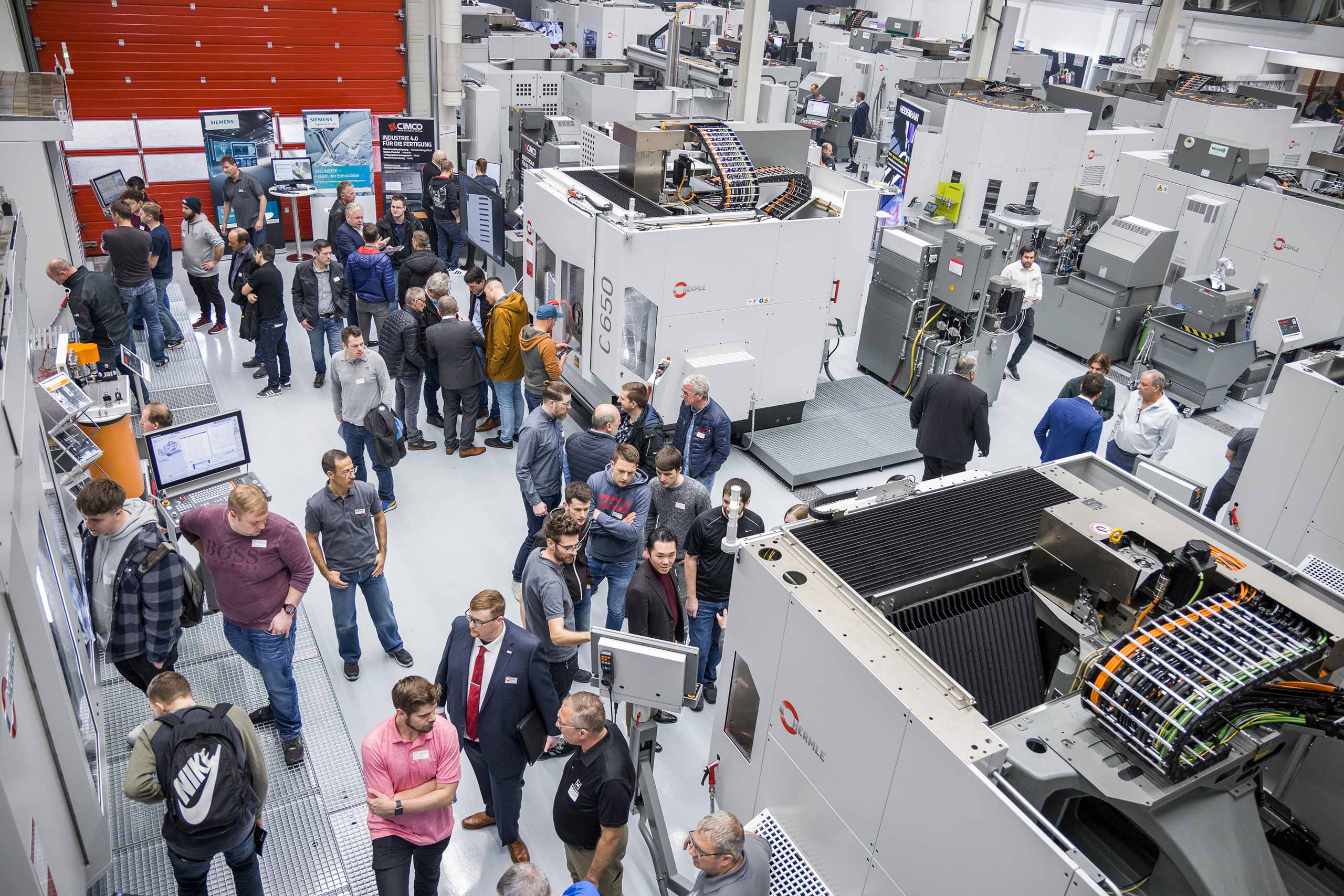 Besucher schauen sich die ausgestellten Maschinen auf der Hermle Hauptausstellung an